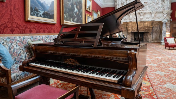 The Broadwood grand piano on display in the Drawing Room at Cragside House. The piano is presented for playing. The keys are showing, the stand has been propped and the lid is up.